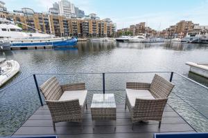 two chairs and a table on a deck with a marina at Serenity in the Heart of London in London