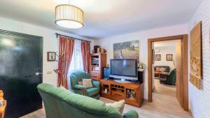 a living room with a green couch and a television at Villa Munoz Ronda by Ruralidays in Ronda