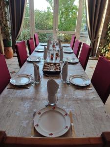 una larga mesa de madera con platos y servilletas. en Les Bienfaits d'Harmonium, en La Chapelle-Gaudin