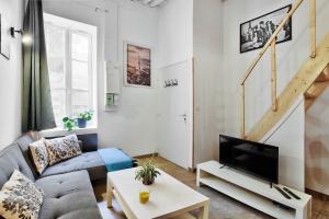 a living room with a couch and a tv at Le cocon de Saint-Clair in Caluire-et-Cuire