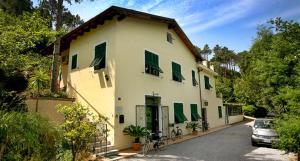 a white house with green shuttered windows and a car at B&B Casale Coreallo Spotorno in Spotorno