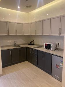 a kitchen with black cabinets and a microwave at رفان للشقق المخدومة in Khamis Mushayt