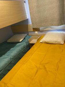 Ce lit se trouve dans un dortoir doté d'une couverture jaune. dans l'établissement Mobil Home cosy 5 personnes proche du Puy Du Fou, à La Boissière-de-Montaigu