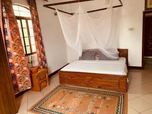 een slaapkamer met een hemelbed en een tapijt bij Good Vibes Stay in Dar es Salaam