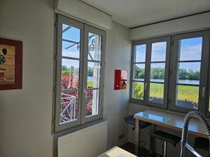 uma sala de espera com três janelas e uma mesa em Entre Château et Loire. em Chaumont-sur-Loire