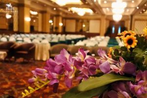 Ein paar lila Blumen in einem Zimmer mit Stühlen in der Unterkunft Grand Aquila Hotel in Bandung