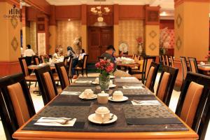 einen langen Tisch in einem Restaurant mit Tischen in der Unterkunft Grand Aquila Hotel in Bandung