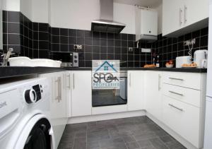 uma cozinha com armários brancos e uma máquina de lavar e secar roupa em Cosy 2BR Home-4 Guests-Business-Families-Netflix-Free Parking & WiFi em Caerleon