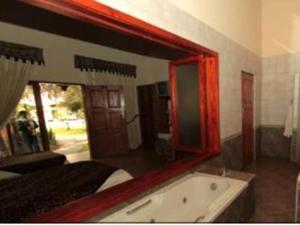 Chrismar Hotel في Riverside: حمام مع مرآة كبيرة وحوض استحمام