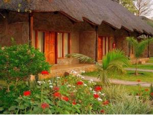 a house with a thatch roof and a garden with flowers at Chrismar Hotel in Riverside