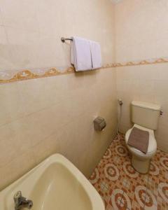 a bathroom with a toilet and a bath tub at UNY Hotel in Demangan