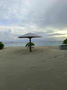 un paraguas sentado en una playa cerca del océano en Turtle Inn Dharavandhoo, en Dharavandhoo