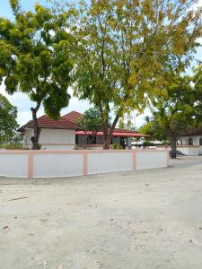una cerca blanca frente a una casa con árboles en Turtle Inn Dharavandhoo, en Dharavandhoo