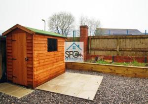a small wooden shed sitting next to a fence at Modern 3BR Home-5 Guests-Business-Families-Netflix-Free Parking & WiFi in Cefn-coed-y-cymmer