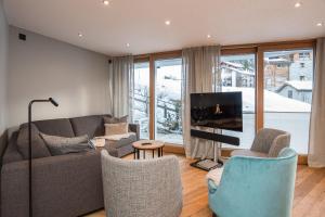 a living room with a couch and chairs and a tv at Angelina in Zermatt