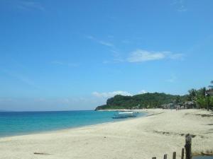 a beach with a boat on the sand and the ocean at Filipiniana Hotel Calapan in Calapan