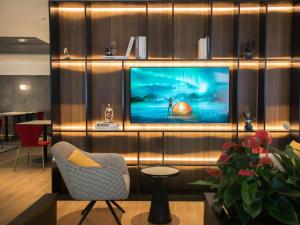 a living room with a television on a wall at Magnotel Business Shanghai New International Exhibition Center in Shanghai