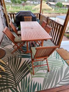 a wooden table and chairs on a porch with a rug at Mobil home tout confort au Camping Les Viviers, Cap Ferret in Claouey