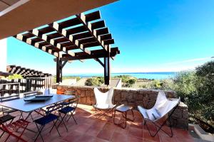 un patio con mesa, sillas y el océano en Location villa 3 chambres vue mer Bonifacio, en Bonifacio