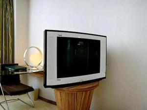 a television sitting on a wooden stand in a room at Orient Sunseed Hotel Airport Branch in Fenghuangwei