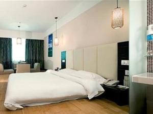 FenghuangweiにあるOrient Sunseed Hotel Airport Branchのベッドルーム(大きな白いベッド1台付)、リビングルームが備わります。