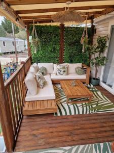 a patio with couches and a table on a deck at Mobil home tout confort au Camping Les Viviers, Cap Ferret in Claouey