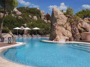 a large swimming pool with chairs and a mountain at D - Resort Ayvalık in Ayvalık