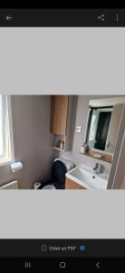 La salle de bains est pourvue d'un lavabo et d'un miroir. dans l'établissement Mobil home tout confort au Camping Les Viviers, Cap Ferret, à Claouey