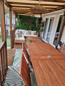 Mobil home tout confort au Camping Les Viviers, Cap Ferret في Claouey: سطح خشبي مع أريكة ومظلة