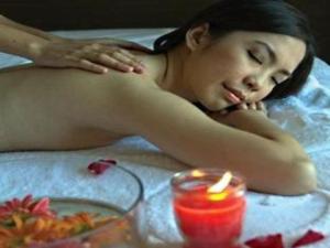Eine Frau, die mit einer Kerze im Bett liegt. in der Unterkunft Ciriaco Hotel in Calbayog