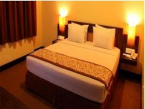 um quarto com uma cama grande e 2 candeeiros em Abadi Hotel Sarolangun by Tritama Hospitality em Sarolangun