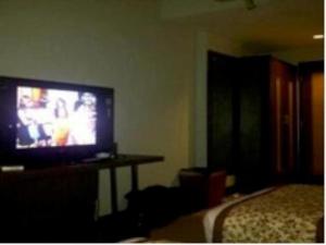 uma sala de estar com televisão e uma cama em Abadi Hotel Sarolangun by Tritama Hospitality em Sarolangun