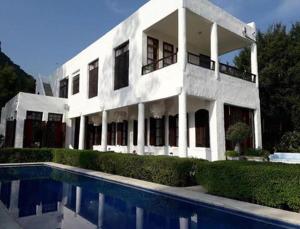 a white house with a swimming pool in front of it at Brassiere Beach Hotel in Baanphakrimlay  +175 photos
