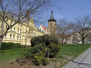 un grand bâtiment avec une tour d'horloge dans un parc dans l'établissement Hotel PurPur, à Prague