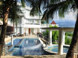 a swimming pool in front of a building with palm trees at Hotel Minahasa in Manado