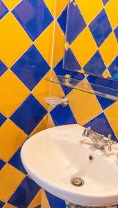 アテネにあるTsilo Cozy Apartの青と黄色のタイルを使用したバスルーム(白い洗面台付)