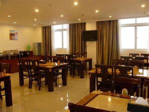 a restaurant with tables and chairs and a television at GreenTree Inn Bozhou Weiwu Road Hotel in Bozhou