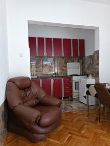 una sedia in pelle marrone in una cucina con armadi rossi di Apartment CENTAR a Šabac