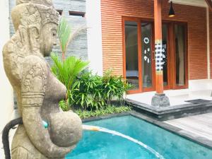 una piscina con statua accanto a una casa di Londo Villa at Londo House ad Ubud