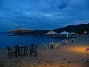 un gruppo di tavoli e sedie su una spiaggia di notte di Country Inn The White Marine a Tonosho