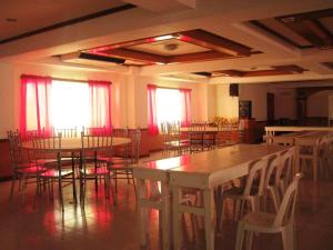 a room with tables and chairs and red curtains at Magayon Hotel in Buenavista