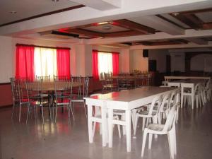 a dining room with tables and chairs and red curtains at Magayon Hotel in Buenavista