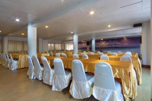 um salão de banquetes com mesas longas e cadeiras brancas em Cha Am Villa Beach em Ban Sahakham