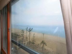 a window with a view of a beach and the ocean at Goodstay Soo Hotel in Gangneung
