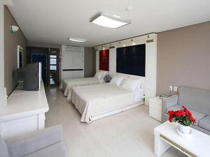 a bedroom with two beds and a tv and a couch at Goodstay Soo Hotel in Gangneung