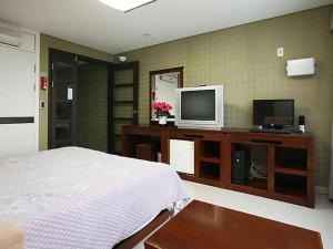 a bedroom with a bed and a flat screen tv at Goodstay Soo Hotel in Gangneung