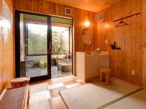 a bathroom with wooden walls and a large sliding glass door at Nanaironoyu Hotel in Takeo
