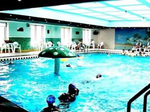 uma piscina com pessoas na água e um guarda-sol em Jincheng Pacific Hotel em Jingcheng
