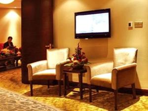 uma sala de espera com duas cadeiras e uma televisão de ecrã plano em Jincheng Pacific Hotel em Jingcheng