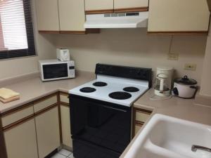 a kitchen with a black stove and a sink at Guam Airport Hotel in Tumon